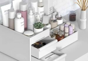 Organizador de maquillaje de plástico con múltiples compartimentos superiores y cajones deslizantes